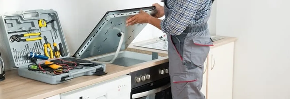 Cooktop repair technician lifting a built-in stovetop for service in Yonkers, NY