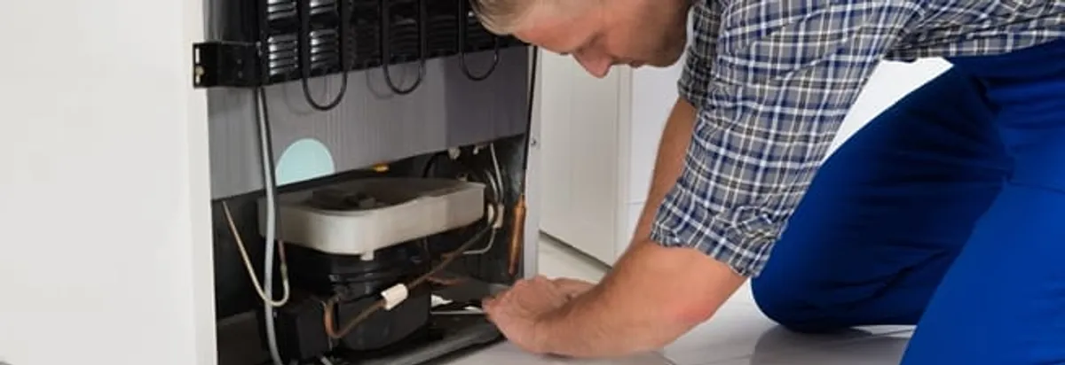 Refrigerator repair technician servicing the compressor and condenser area in Yonkers, NY