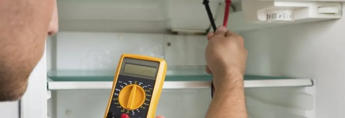 Refrigerator repair technician testing electrical components with a multimeter in Yonkers, NY