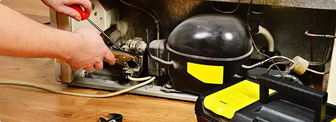 Refrigerator repair technician fixing the compressor and wiring in Yonkers, NY